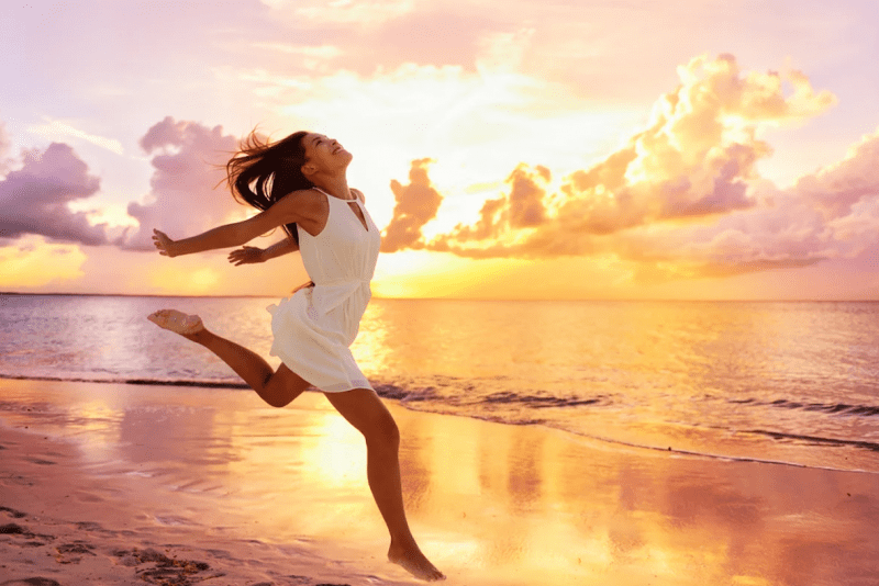 Девушка бежит по пляжу на фоне заката