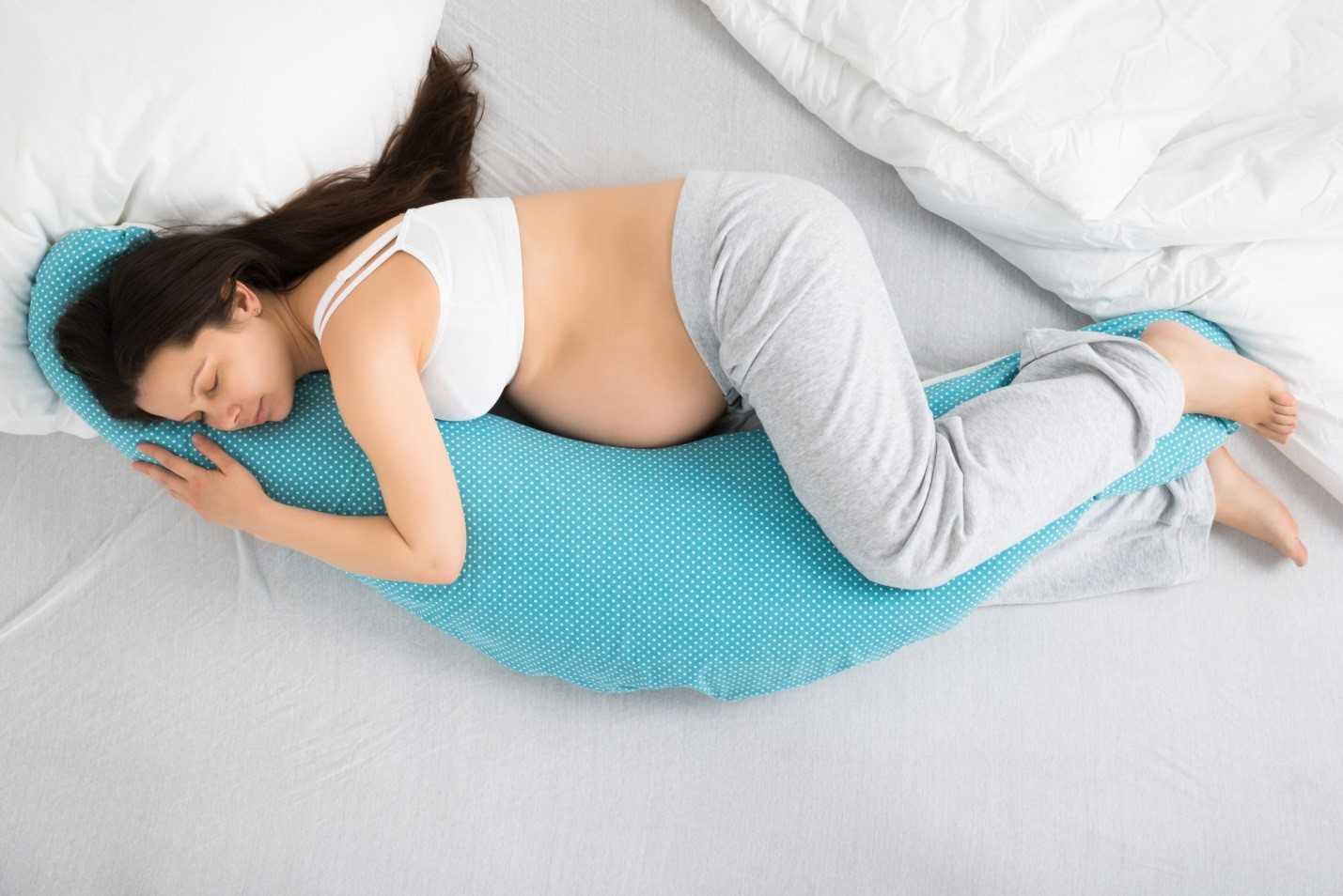 Женщина спит на голубой подушке для беременных